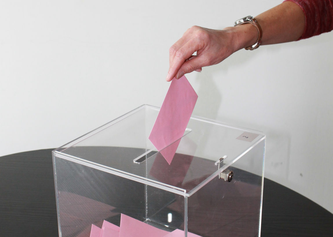 Gros plan photo d'une personne déposant un bulletin de vote dans une urne | Myriam Lakraa